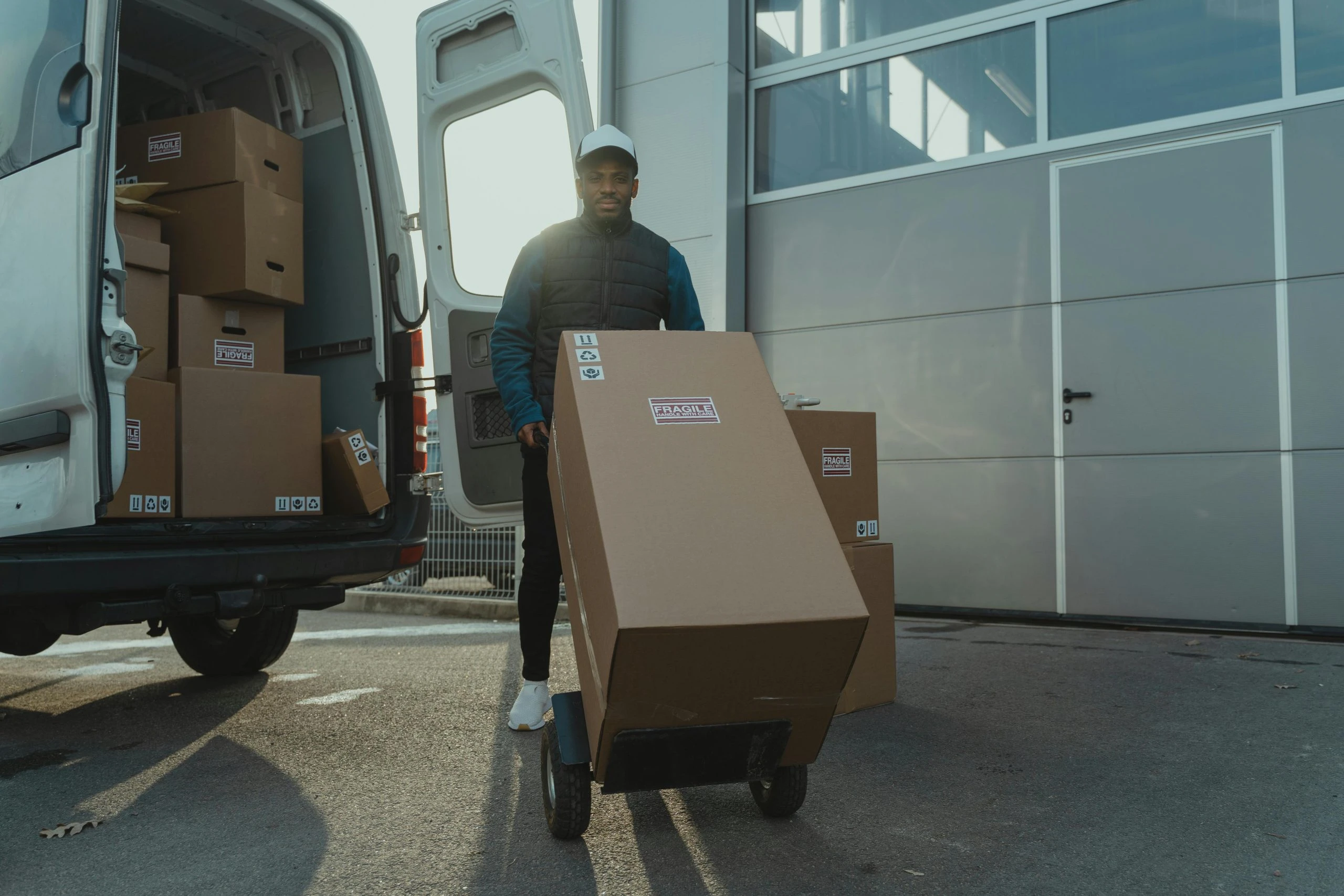 Delivery person moving a large box with a hand truck.