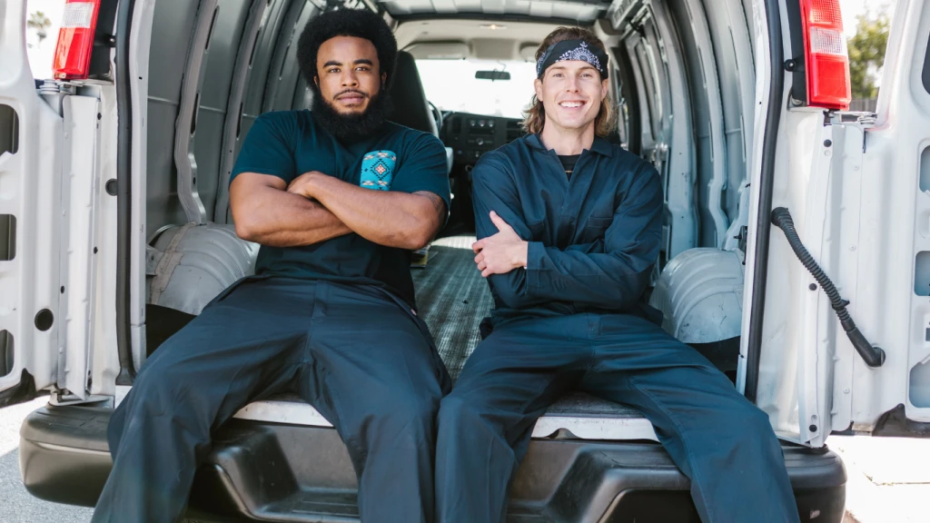 Two men in workwear sitting in the back of van.