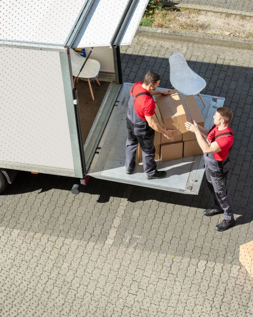 High-angle view of two movers loading boxes into a truck.